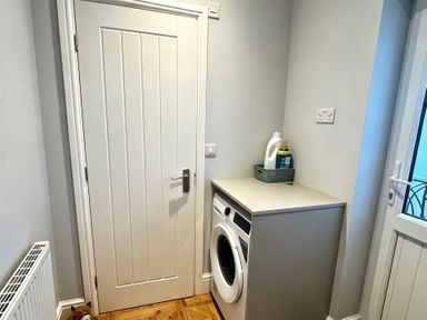 A laundry room with a washing machine and a door at Jacks Place in Whitby