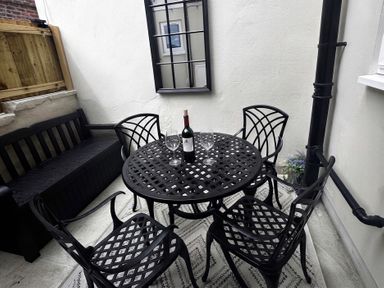 An outdoor seating area with a round table, chairs, and a bench at Jacks Place in Whitby