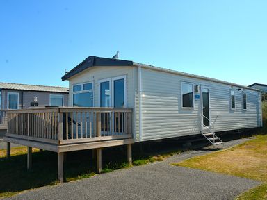 A mobile home with a deck and steps at Perran Sands Holiday Park - 725 Kernow View Perranporth