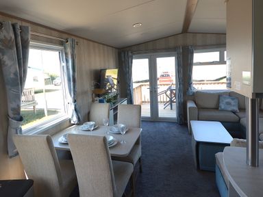 A living room with a dining area and sofa at Perran Sands Holiday Park - 725 Kernow View, Perranporth