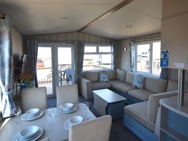 A living room with a sofa and dining table at Perran Sands Holiday Park - 725 Kernow View in Perranporth
