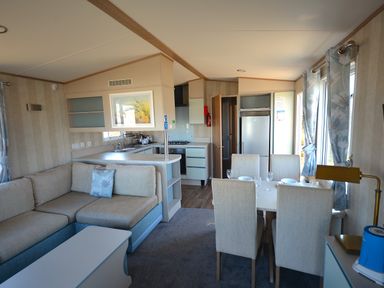 A living room with a sofa and dining area at Perran Sands Holiday Park - 725 Kernow View Perranporth