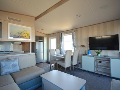 A living room with a sofa, dining table and television at Perran Sands Holiday Park - 725 Kernow View in Perranporth