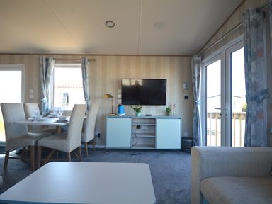 A dining area with seating and a television at Perran Sands Holiday Park - 725 Kernow View, Perranporth