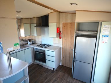 A kitchen with an oven, stove, and stainless steel refrigerator at Perran Sands Holiday Park - 725 Kernow View Perranporth