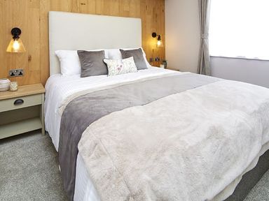 A bedroom with a bed and bedside table at Hoburne Devon Bay - Woodland Glade 24 in Paignton