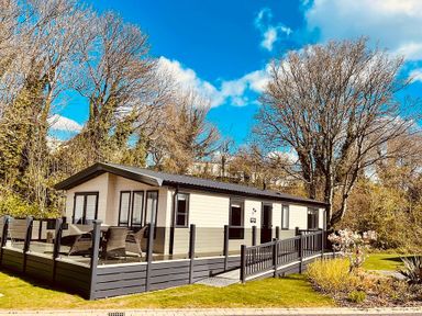 A cabin with decking and chairs at Hoburne Devon Bay - Woodland Glade 24 Paignton
