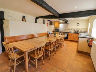 A kitchen with wooden dining table and chairs with kitchen appliances and black ceiling beams at Little Cowarne Court in Little Cowarne near Bromyard