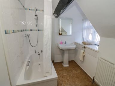 A bathroom with a bathtub shower combination sink with mirror and a window with towels on the sill at Little Cowarne Court in Little Cowarne near Bromyard