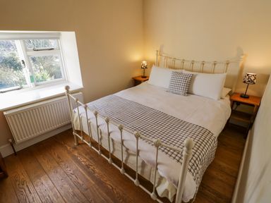 A bedroom with a white metal bed frame a bed with checked bedding two bedside tables with lamps and a window at Little Cowarne Court in Little Cowarne near Bromyard