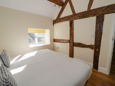 A bedroom with a double bed near a window with wooden beams on the wall at Little Cowarne Court in Little Cowarne near Bromyard