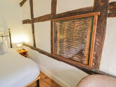 A bedroom corner with a bed and bedside table next to a timber framed wall panel at Little Cowarne Court in Little Cowarne near Bromyard