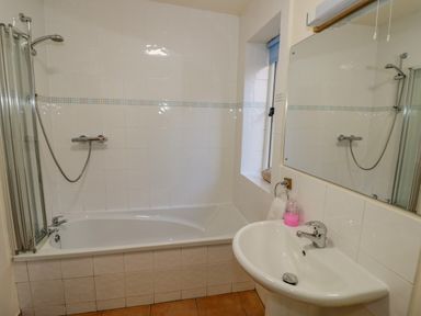 A bathroom with a bathtub shower combination and a sink with a mirror at Little Cowarne Court in Little Cowarne near Bromyard