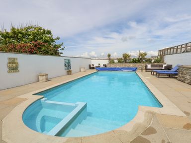 An outdoor swimming pool with a seating area and sun loungers surrounding it at Old Higher Lighthouse Stopes Cottage in Portland Bill