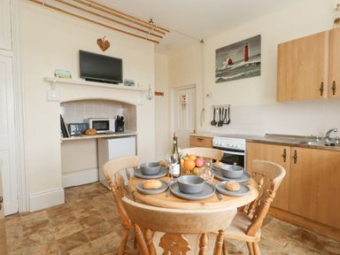 A kitchen with a wooden dining table set with bowls and bread and wooden chairs at Old Higher Lighthouse Stopes Cottage Portland Bill