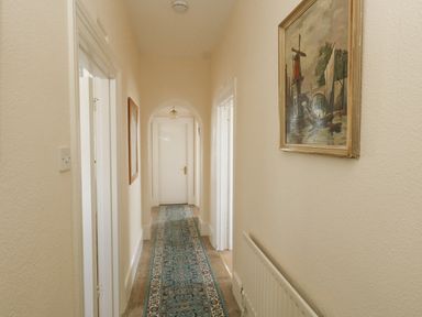 A hallway with doors along the sides a radiator and a painting on the wall at Old Higher Lighthouse Stopes Cottage Portland Bill