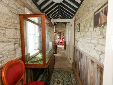 A narrow hallway with stone walls a glass display cabinet and red chairs at Old Higher Lighthouse Stopes Cottage Portland Bill