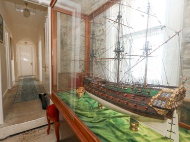 A hallway with a blue runner rug and a ship model in a glass case at Old Higher Lighthouse Stopes Cottage Portland Bill