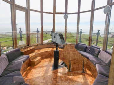 A room with curved seating and a mounted viewing device surrounded by large windows at Old Higher Lighthouse Stopes Cottage Portland Bill