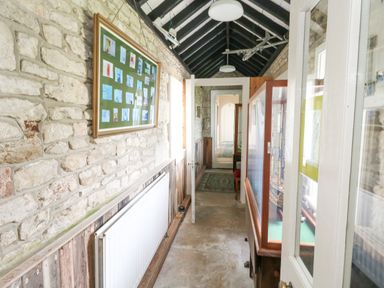 A narrow corridor with stone walls a radiator on the left and a display cabinet on the right at Old Higher Lighthouse Stopes Cottage in Portland Bill