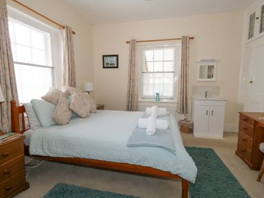 A bedroom with a double bed pillows bedside tables a washbasin and windows at Old Higher Lighthouse Stopes Cottage in Portland Bill