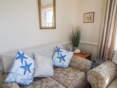 A living room with a sofa and cushions at Old Higher Lighthouse Stopes Cottage in Portland Bill