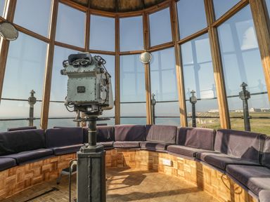 An observation room with large windows a mounted binocular viewer and a circular bench with cushions at Old Higher Lighthouse Branscombe Lodge Portland Bill