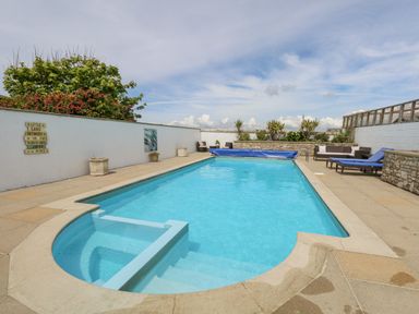 An outdoor swimming pool with lounge chairs and plants at Old Higher Lighthouse Branscombe Lodge Portland Bill