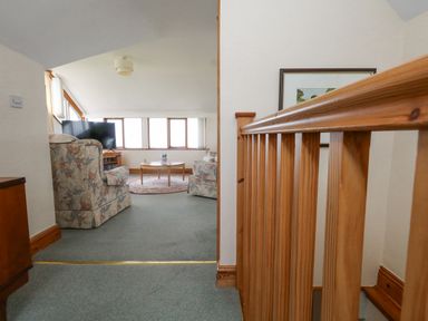A living room with floral armchairs a round coffee table and a television near windows at Old Higher Lighthouse Branscombe Lodge Portland Bill