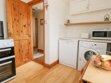 A kitchen with a wooden door dishwasher washing machine microwave and fruit bowl at Old Higher Lighthouse Branscombe Lodge Portland Bill