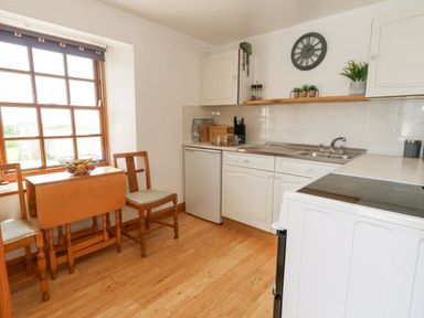 A kitchen with wooden chairs and table a sink refrigerator and stove at Old Higher Lighthouse Branscombe Lodge Portland Bill