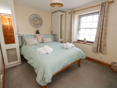 A bedroom with a double bed with pillows and towels next to a window with curtains at Old Higher Lighthouse Branscombe Lodge Portland Bill
