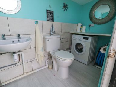 A bathroom with a sink toilet washing machine and mirror at Old Higher Lighthouse Branscombe Lodge Portland Bill