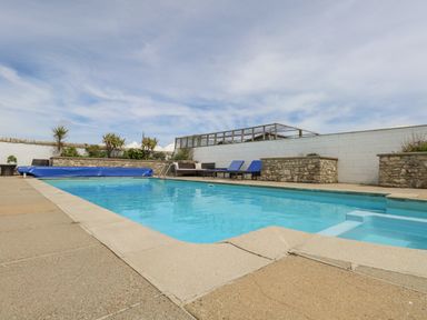 An outdoor swimming pool with blue lounge chairs and potted plants at Old Higher Lighthouse Branscombe Lodge Portland Bill