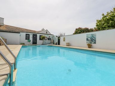 An outdoor swimming pool with steps and metal railing surrounded by a white wall and a building at Old Higher Lighthouse Branscombe Lodge Portland Bill