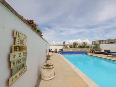 An outdoor swimming pool with seating areas and plants along white walls at Old Higher Lighthouse Branscombe Lodge Portland Bill