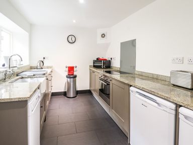 A kitchen with granite countertops appliances a sink and a trash can at 3 Railway Cottages Betws-y-Coed