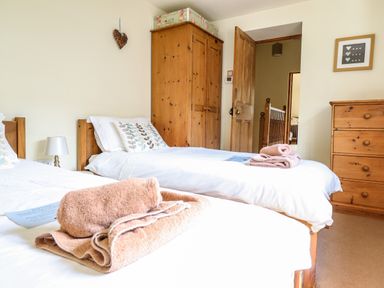 A bedroom with two single beds wooden wardrobe and chest of drawers at 3 Railway Cottages in Betws-y-Coed