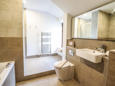 A bathroom with a bathtub toilet sink towel rack and large mirror at 3 Railway Cottages in Betws-y-Coed