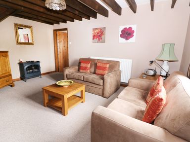 A living room with beige sofas and wooden coffee table at Cedar Cottage in Llanidloes