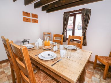 A dining room with wooden table and chairs set for breakfast at Cedar Cottage in Llanidloes