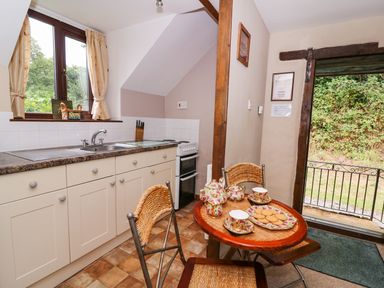 A kitchen with a sink oven and a small table set with tea cups and biscuits at Oak Cottage in Llanidloes
