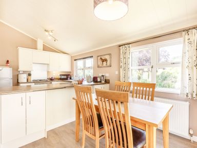 A kitchen with wooden dining table and chairs and white cabinets at Lavender Lodge in Charlton Horethorne near Sherborne
