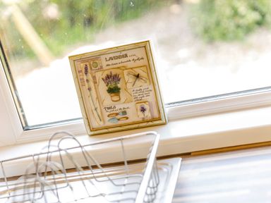 A kitchen window with a decorative lavender plaque on the sill and a metal dish rack at Lavender Lodge Charlton Horethorne near Sherborne
