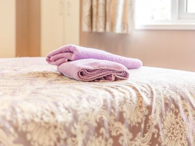 A bed with patterned bedspread and two folded purple towels on top in a bedroom at Lavender Lodge in Charlton Horethorne near Sherborne