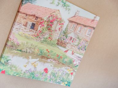 A painting of two stone houses with red roofs by a pond with ducks and flowers at Lavender Lodge Charlton Horethorne near Sherborne