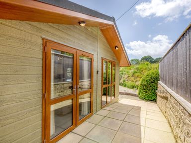 A patio area with double glass doors and windows on a wooden house at Lavender Lodge in Charlton Horethorne near Sherborne