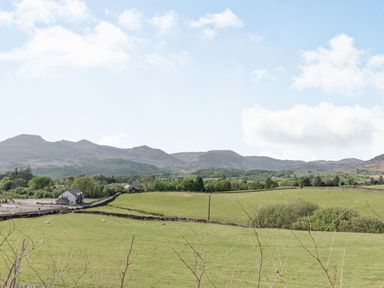 Green fields with sheep and stone fences and a few buildings with mountains in the background at 2 Bryn Tirion in Llan Ffestiniog