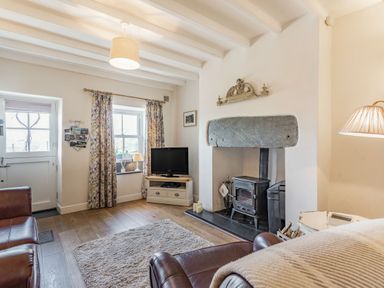 A living room with a wood stove fireplace a television and leather armchairs at 2 Bryn Tirion in Llan Ffestiniog