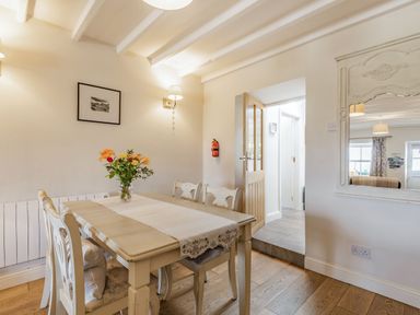 A dining room with a table and chairs a vase with flowers and a mirror on the wall at 2 Bryn Tirion in Llan Ffestiniog
